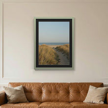 Green picture frame with a black mount hanging on a living room wall