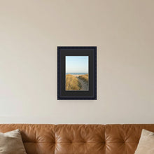 Louis Black picture frame with a black mount hanging on a living room wall