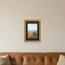 Louis Gold picture frame with a black mount hanging on a living room wall