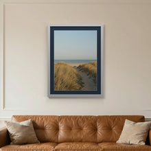 Silver picture frame with a Pacific Blue mount hanging on a living room wall